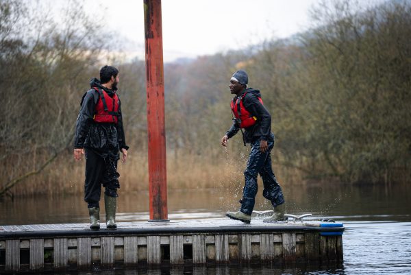 Two StreetGames young advisors on a jetty near a body of water, both wet.
